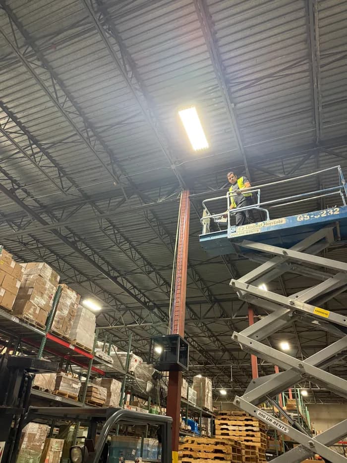 An Insinet technician installing at height from a scissor lift inside a warehouse.