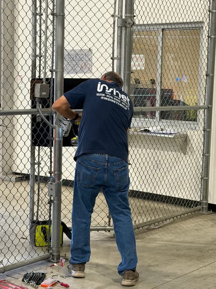 An Insinet technician installing access-control equipment inside a security cage.